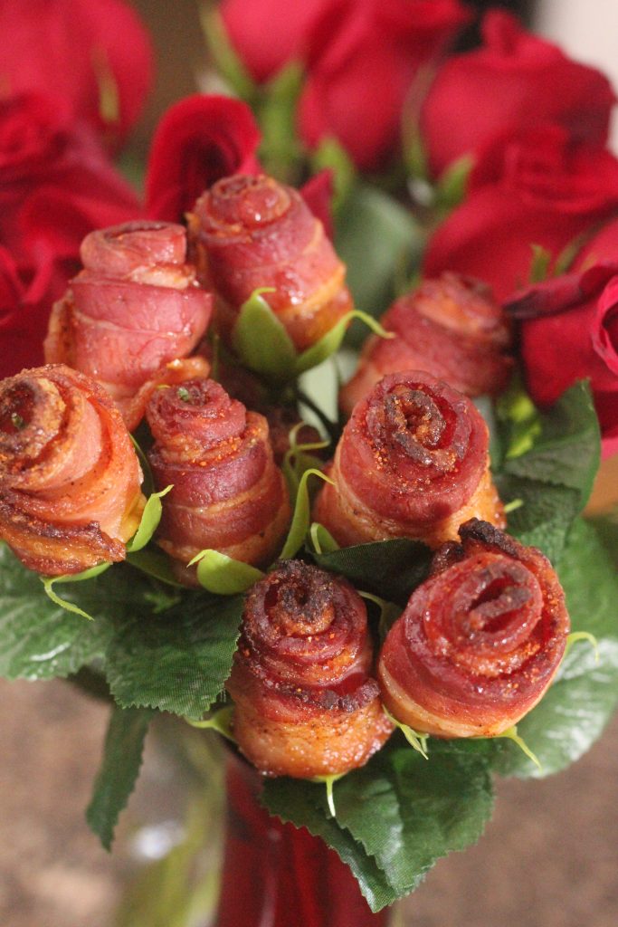 bacon roses in a red glass vase.