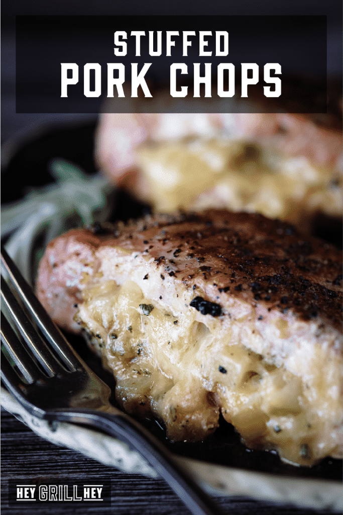 Two stuffed pork chops on a plate next to a metal fork with text overlay - Stuffed Pork Chops.