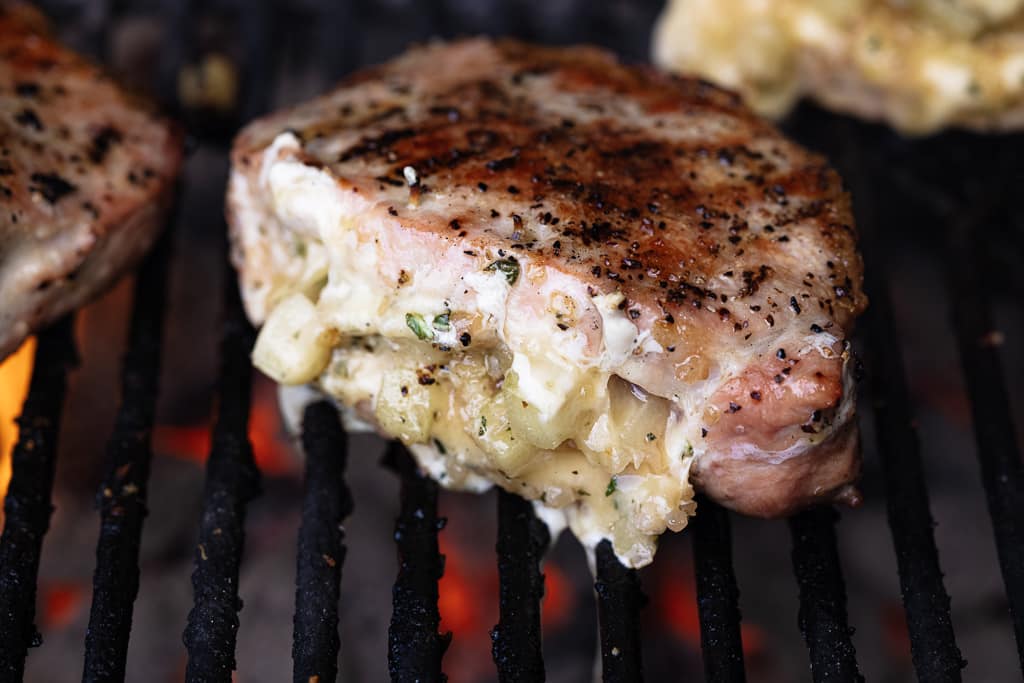 Stuffed pork chop on the grill grates of a charcoal grill.