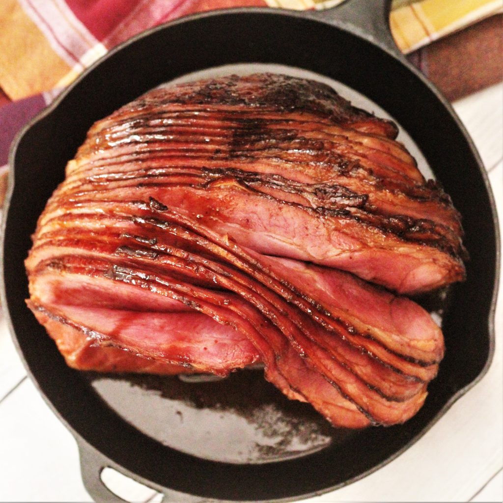 Top view of a spiral sliced twice smoked ham, sitting in a cast iron skillet.