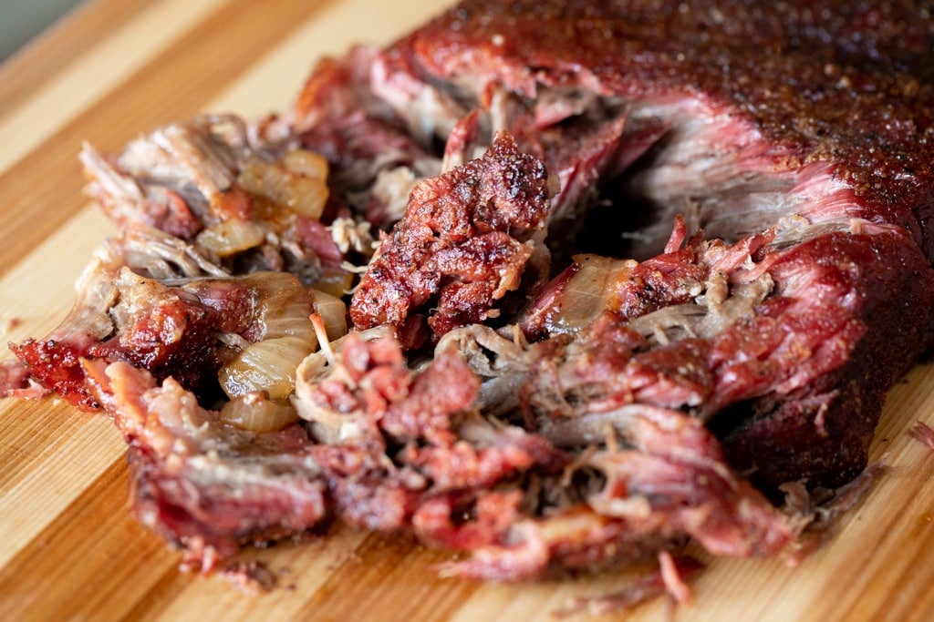 Smoked and shredded smoked chuck roast on a wooden cutting board.
