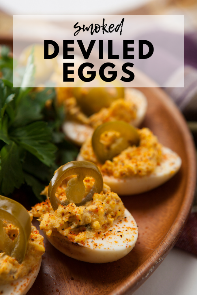 Deviled eggs arranged in a circle on a wooden plate. Text overlay reads, "Smoked Deviled Eggs."