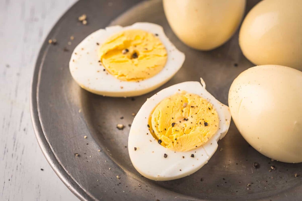 Entire smoked eggs and two half of the smoked eggs on a plate.