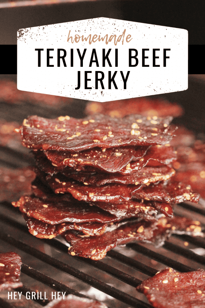 Stack of teriyaki beef jerky on the grill grates of a smoker. Text overlay reads: Homemade Teriyaki Beef Jerky.