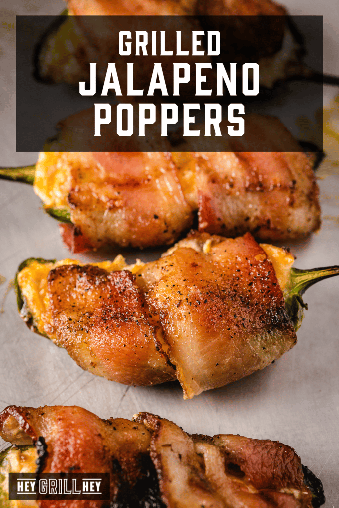 Bacon wrapped grilled jalapeno poppers lined up on a serving dish with text overlay - Grilled Jalapeno Poppers.