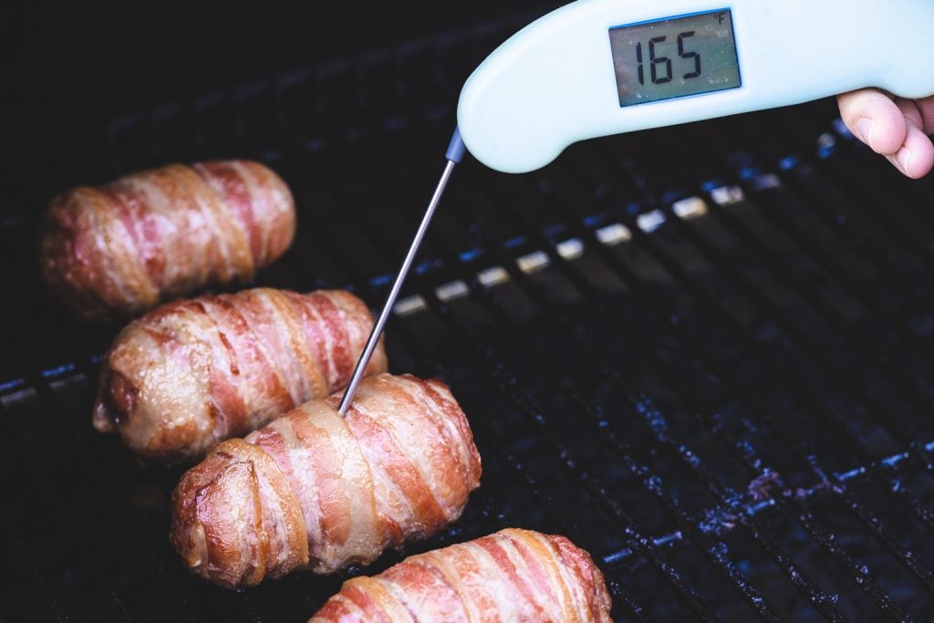 Armadillo eggs on the smoker with an internal thermometer reading 165 degrees F.