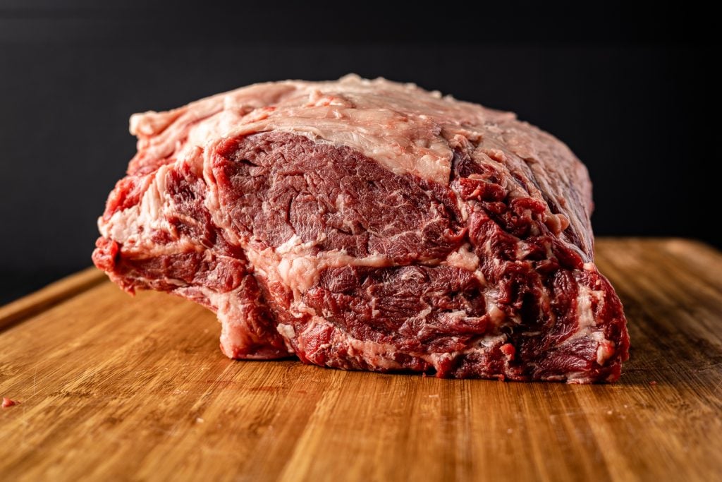 Uncooked prime rib roast on a cutting board.