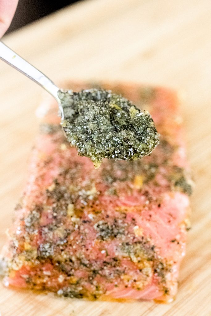 a spoonful of seasoning over a seasoned salmon filet.