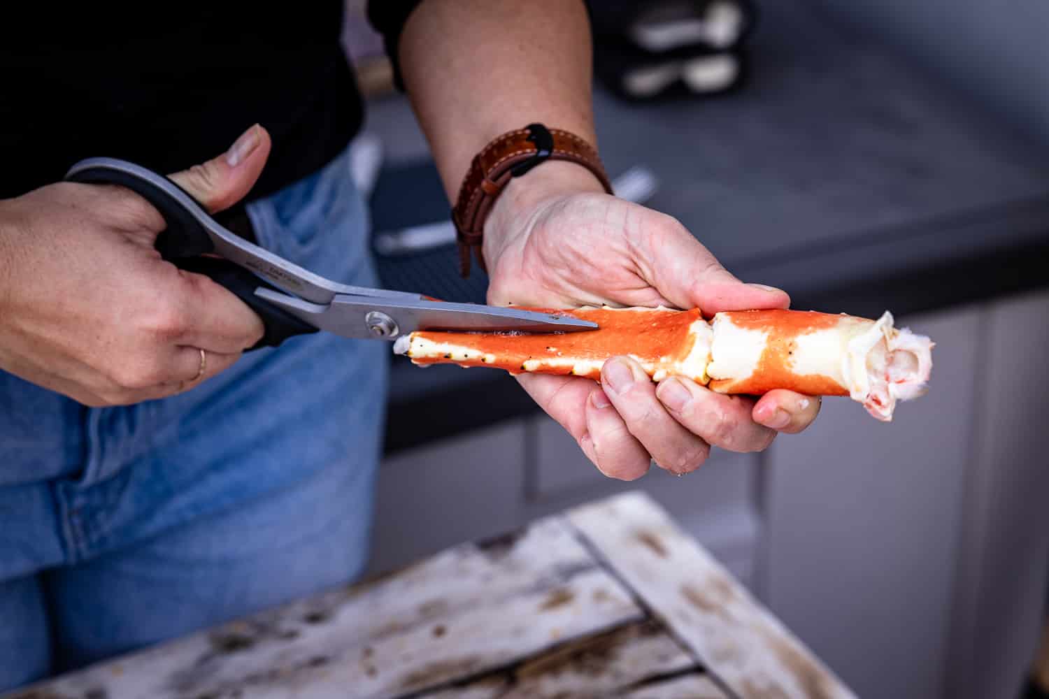 Crab leg being cut lengthwise by a pair of kitchen shears.