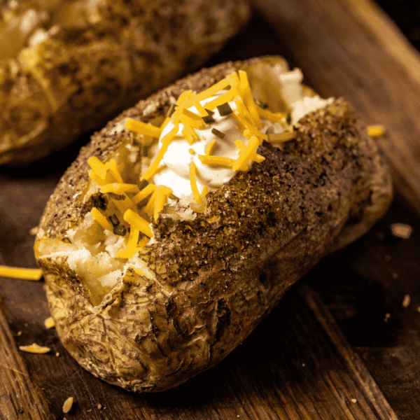 Smoked baked potato topped with shredded cheese and sour cream.