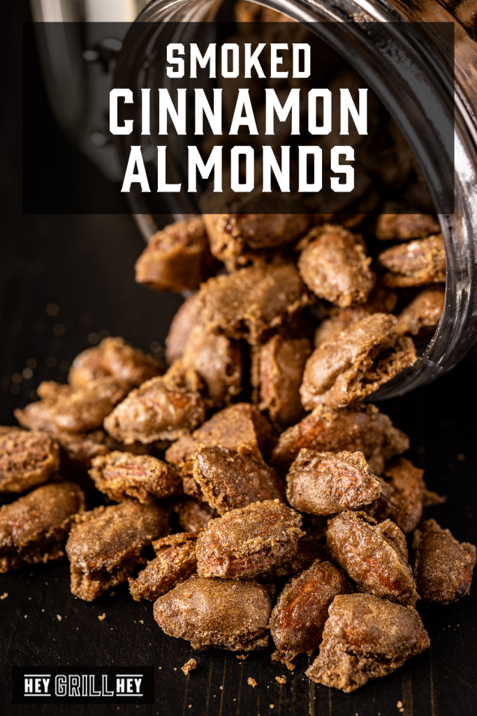 Smoked cinnamon almonds pouring out of a glass mason jar with text overlay - Smoked Cinnamon Almonds.