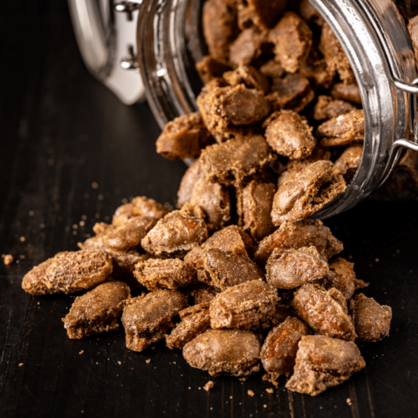 Smoked cinnamon almonds pouring out of a glass mason jar.