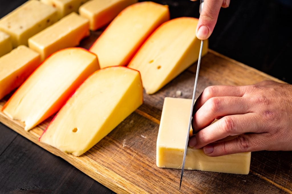 Blocks of cheese being sliced into smaller sizes.