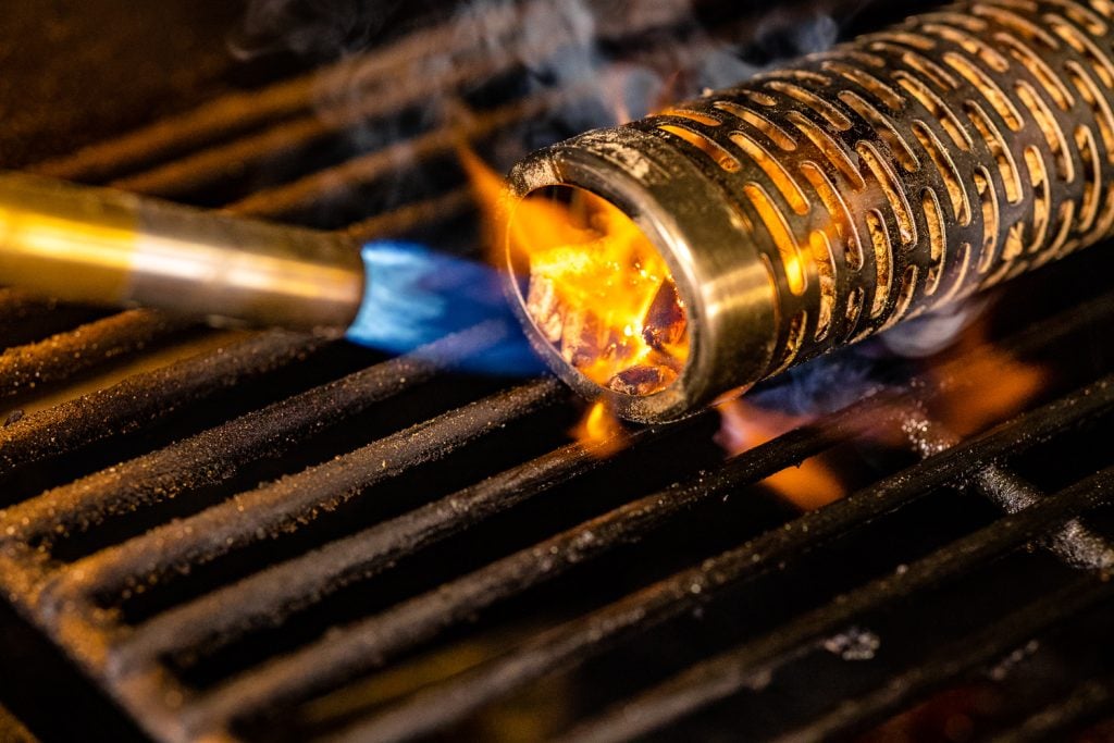 A smoke tube being lit inside a grill.