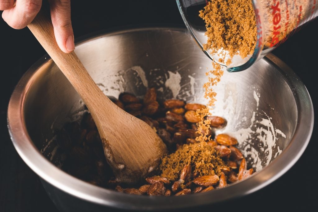 Almonds being coated in brown sugar and cinnnamon.