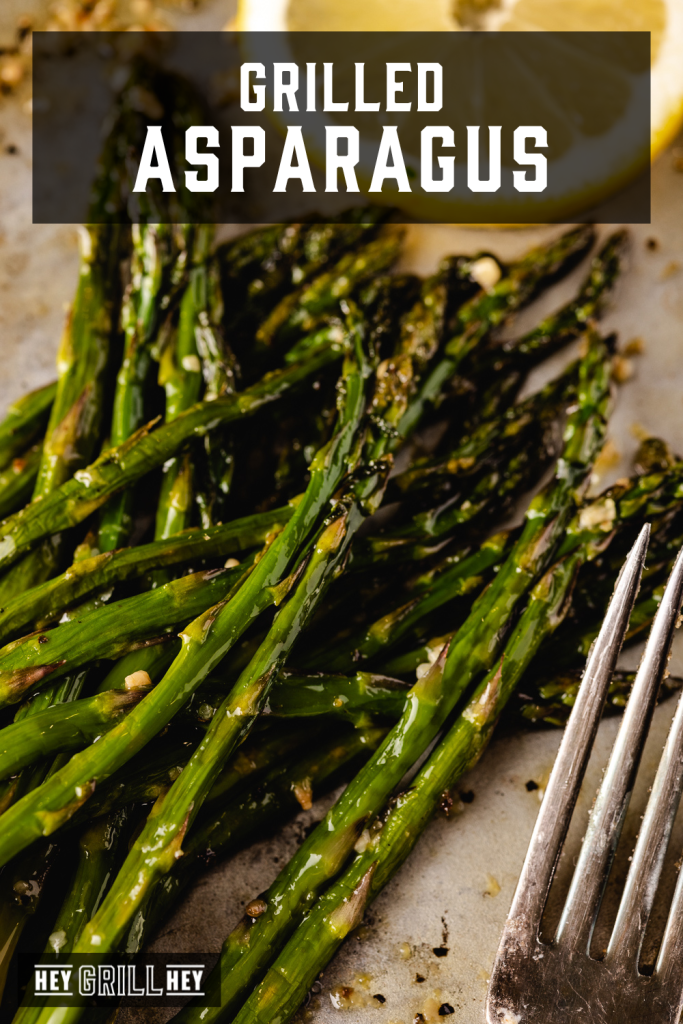 Pile of grilled asparagus next to a lemon slice with text overlay - Grilled Asparagus.