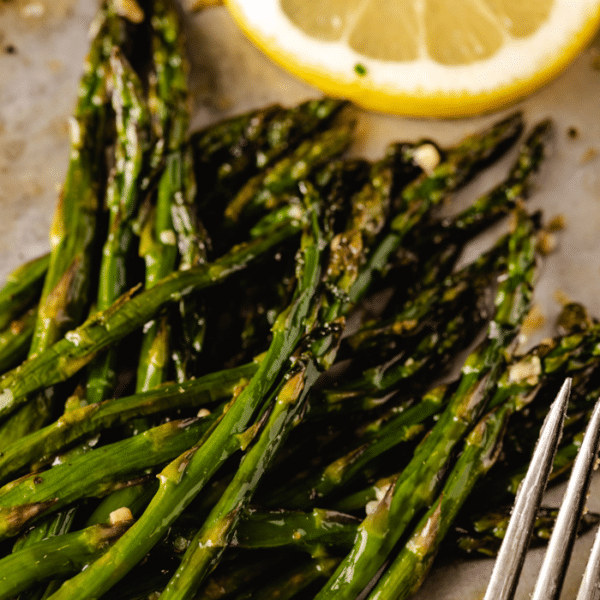 Pile of grilled asparagus next to a lemon slice.