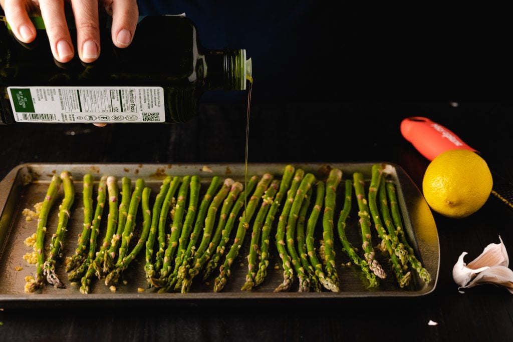 Asparagus being drizzled with olive oil.