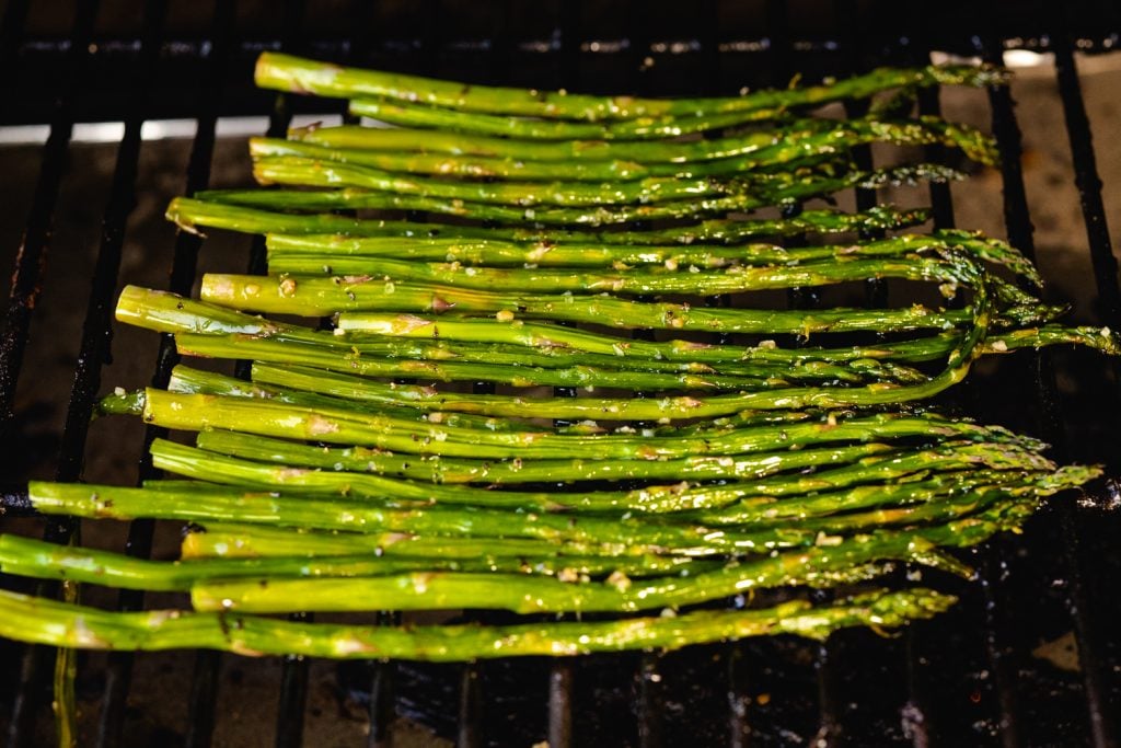 Seasoned spears on the grates of a gas grill.