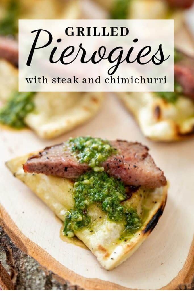 Grilled pierogies topped with grilled steak and chimichurri sauce on a wood board.