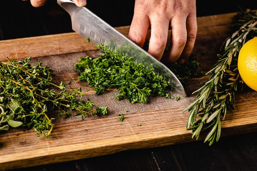 Fresh herbs being chopped on the cutting board.