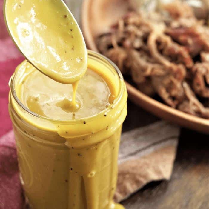 Jar of Carolina mustard BBQ sauce next to a bowl of pulled pork.