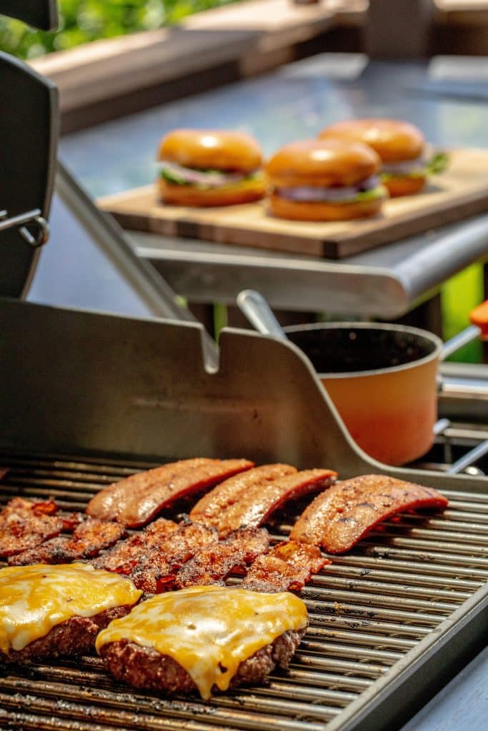 hamburgers, hot dogs, and bacon on a grill grate.