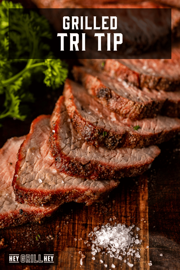 Grilled and sliced tri tip on a wooden board with text overlay - Grilled Tri Tip.