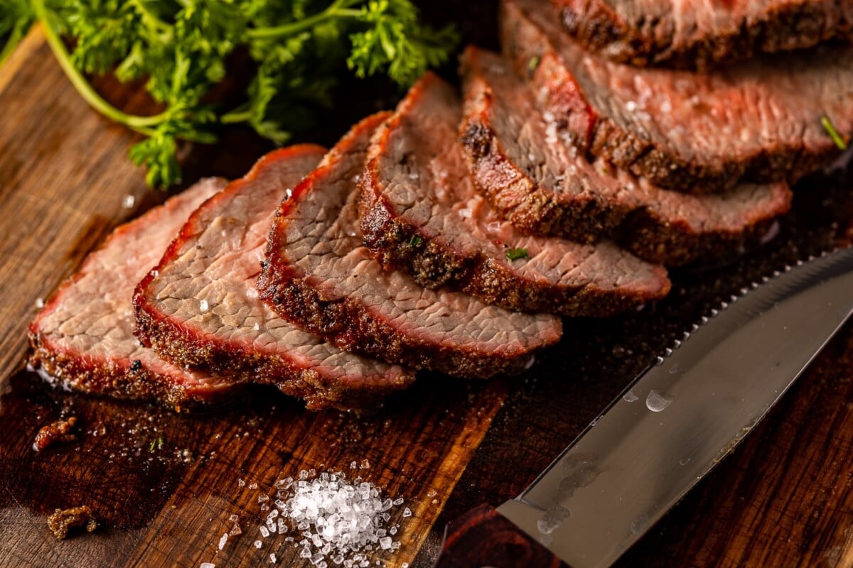 Grilled and sliced tri tip on a wooden board.