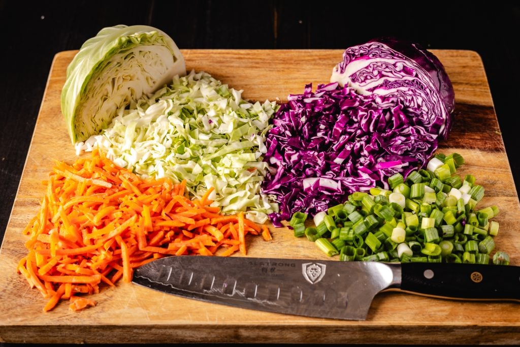 Ingredients for vinegar coleslaw on a wooden cutting board.