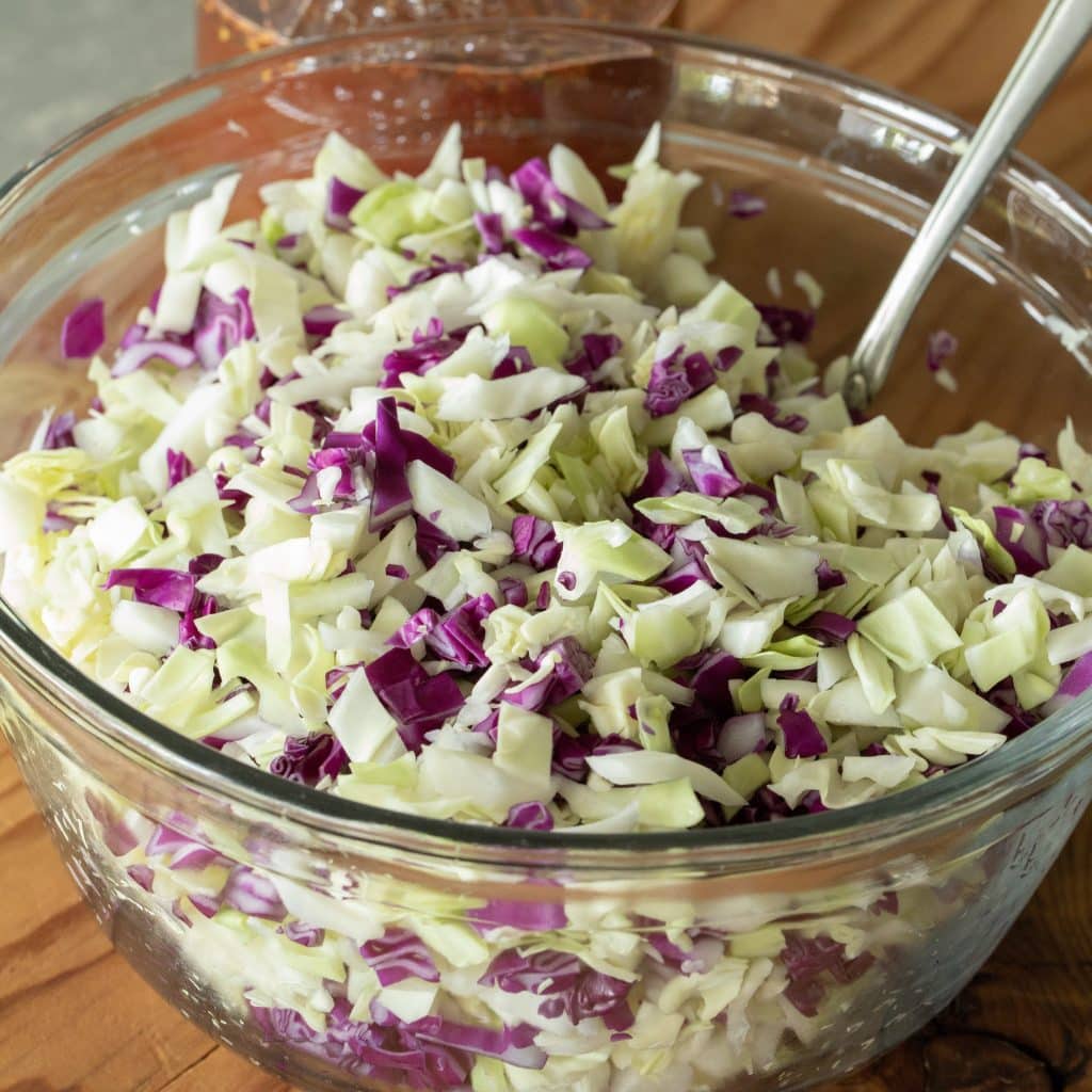 glass bowl of chopped coleslaw with vinegar dressing.