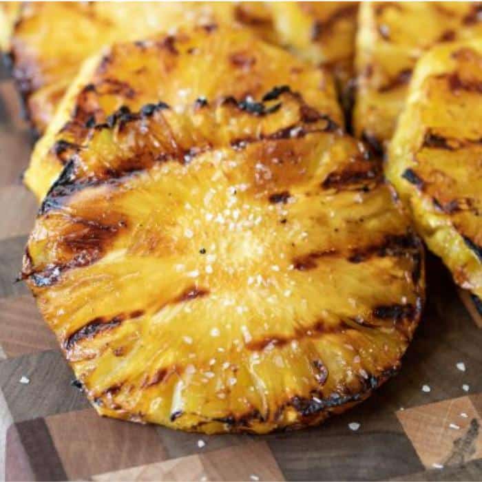 grilled pineapple slices on a wooden cutting board