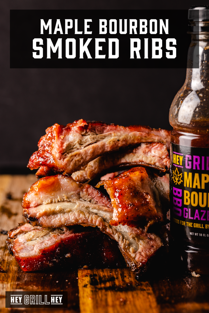 Stack of maple bourbon ribs on a wooden cutting board with text overlay - Maple Bourbon Smoked Ribs.