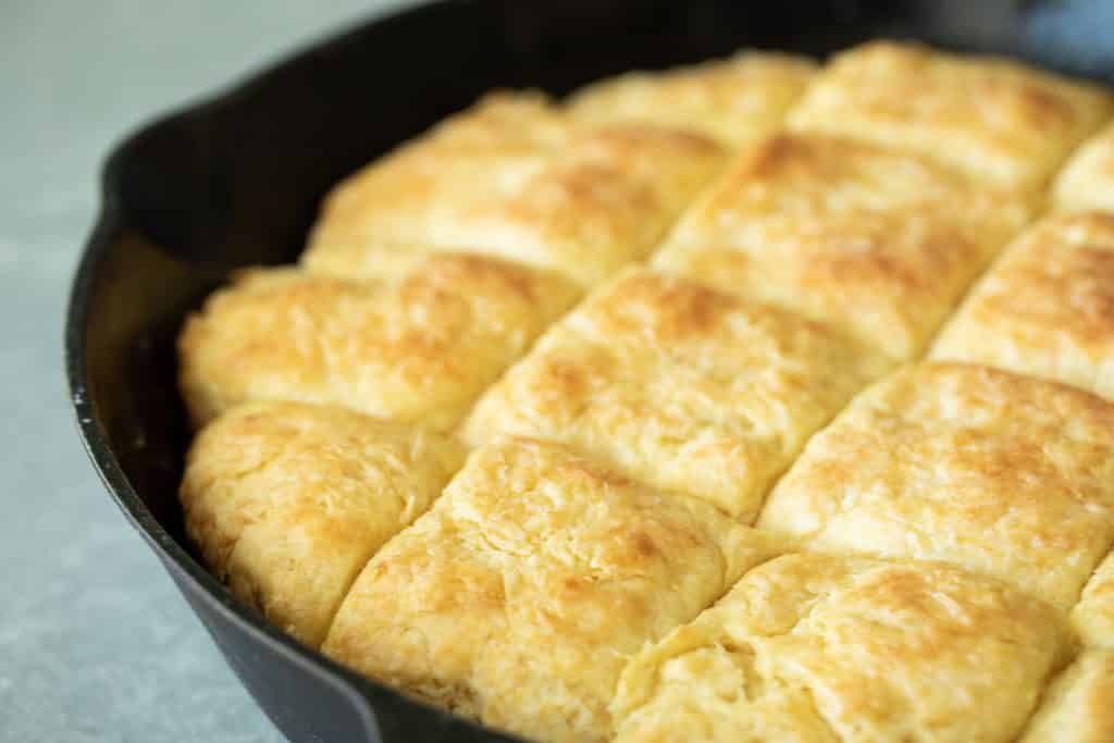 cast iron skillet full of baked and sliced buttermilk buscuits.