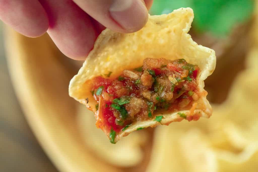 a tortilla chip filled with a scoop of smoked salsa.