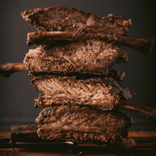 Stack of beef ribs on a wooden cutting board.