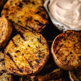 Grilled sweet potato slices next to a bowl of dipping sauce.