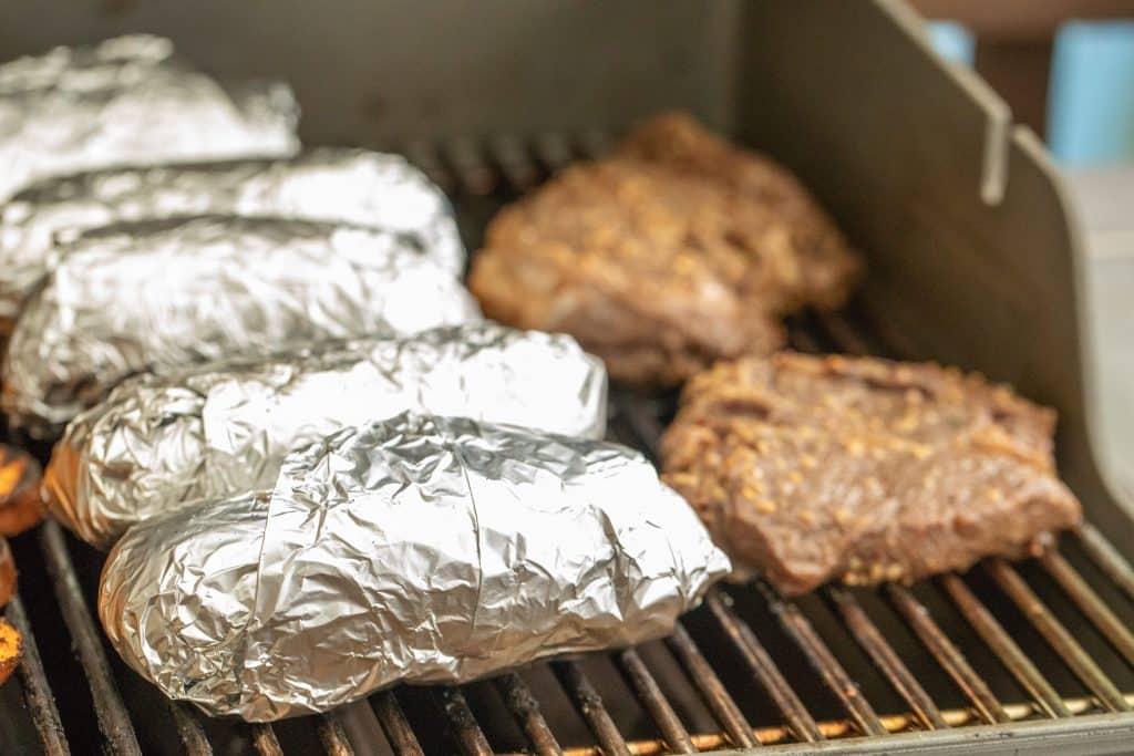 foil-wrapped baked potatoes on the grill
