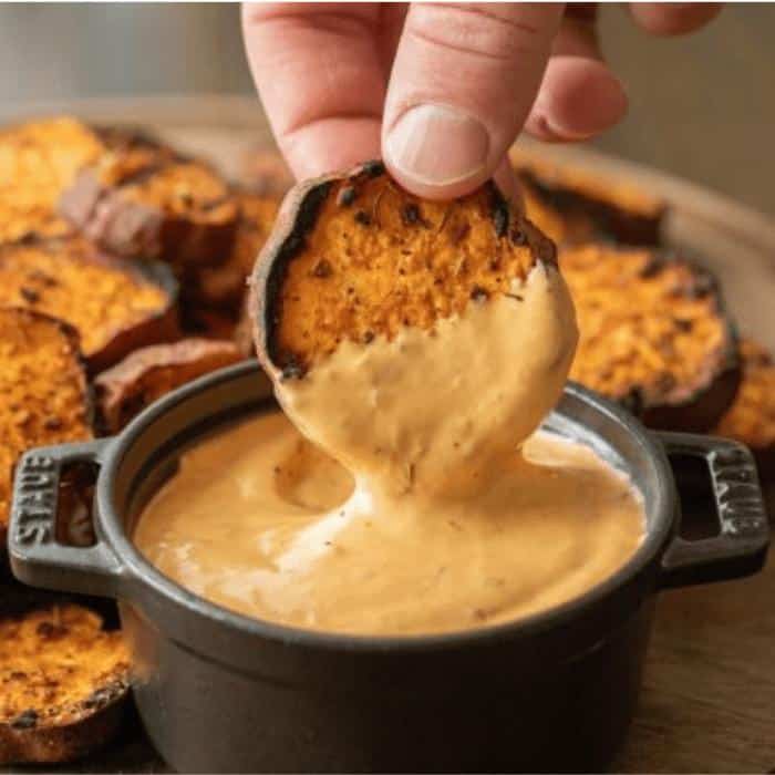 grilled sweet potato being dipped in chipotle dipping sauce