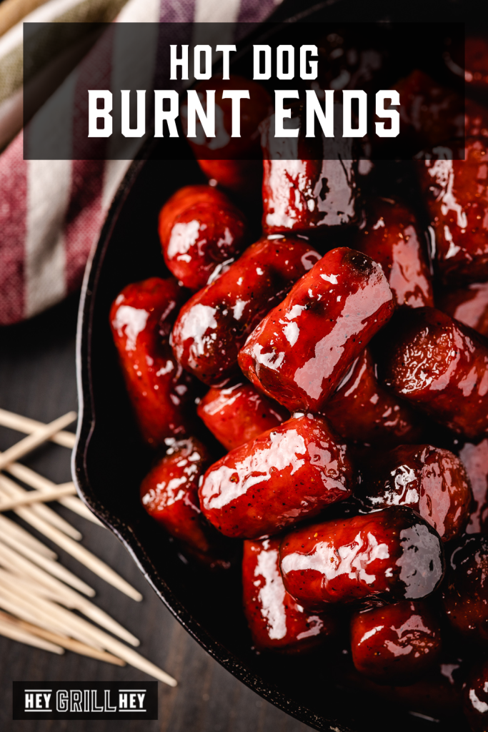 Hot dog burnt ends in a cast iron skillet with text overlay - Hot Dog Burnt Ends.