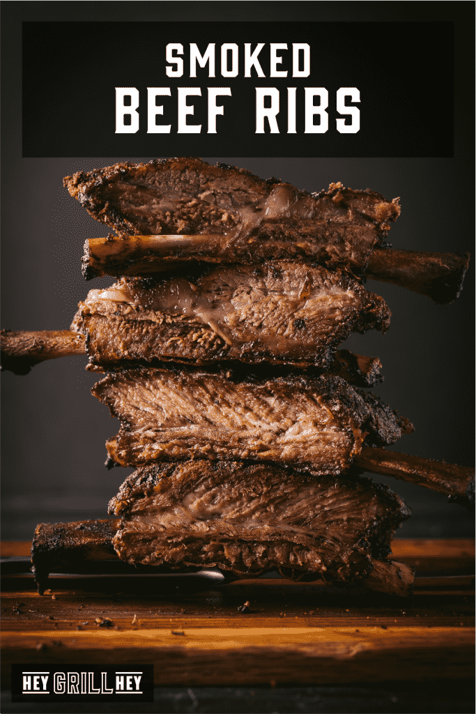 Stack of beef ribs on a wooden cutting board with text overlay - Smoked Beef Ribs.