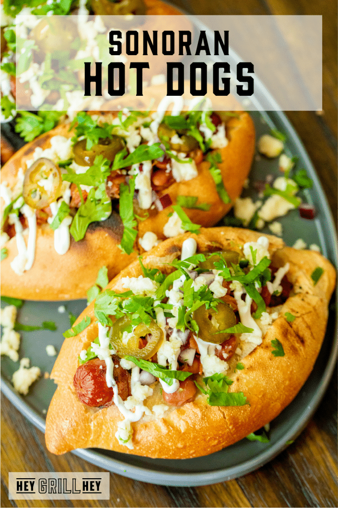 Three loaded sonoran hot dogs on a oval serving dish with text overlay - Sonoran Hot Dogs.