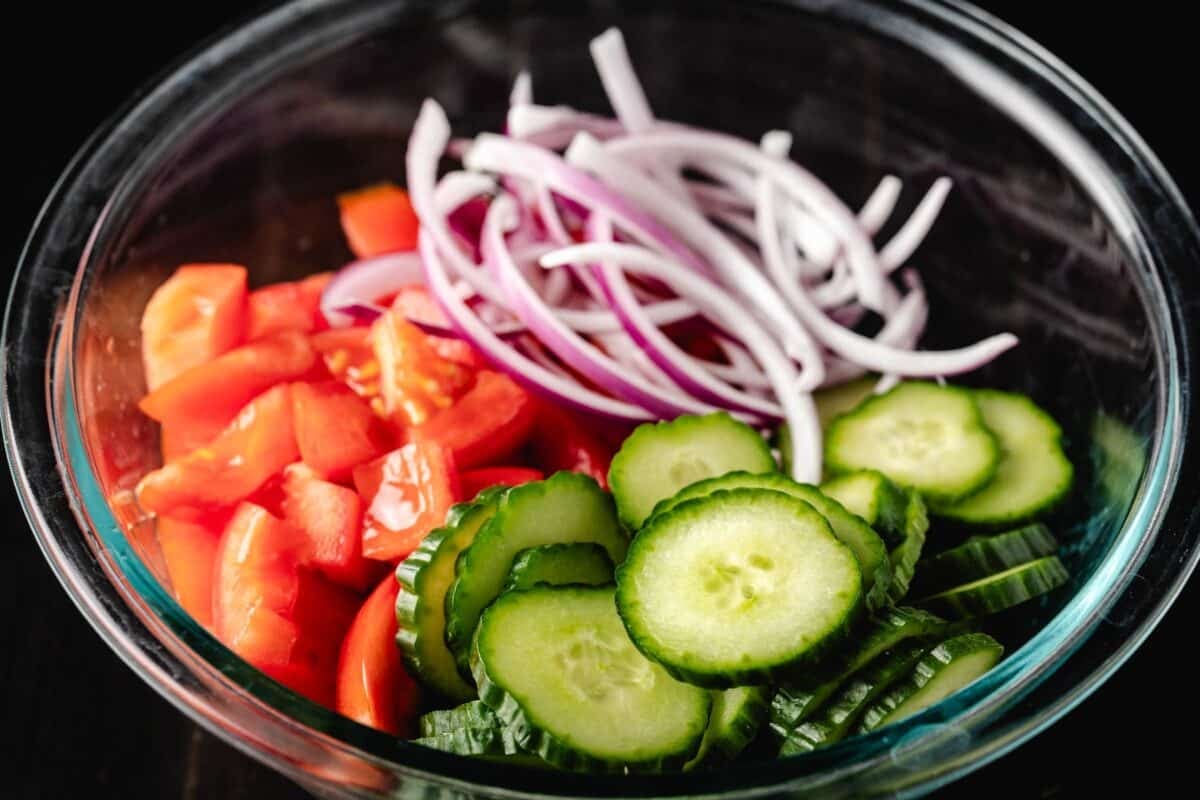 Sliced and chopped vegetables in a glass bowl.