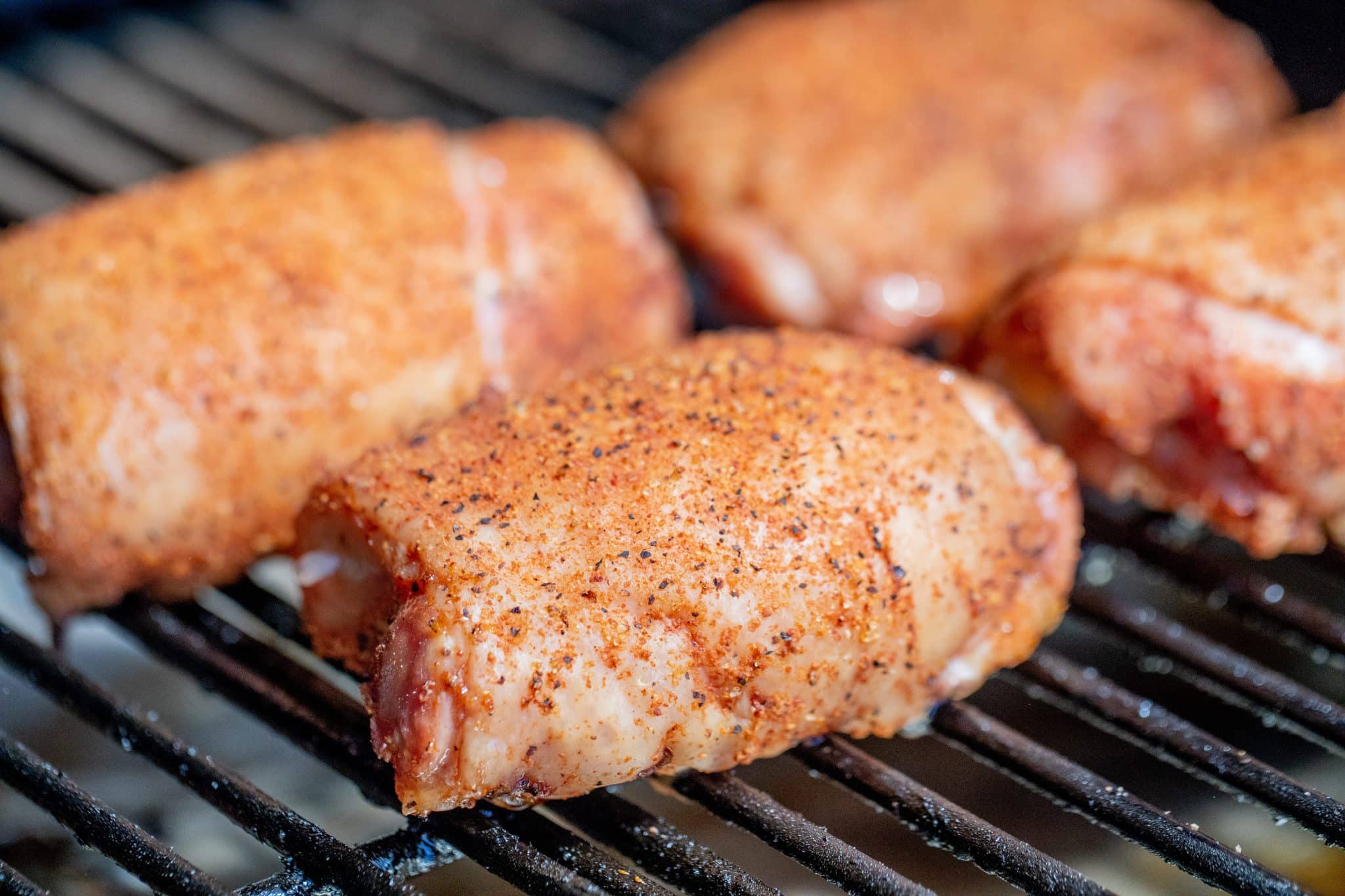 seasoned chicken thighs on a smoker.