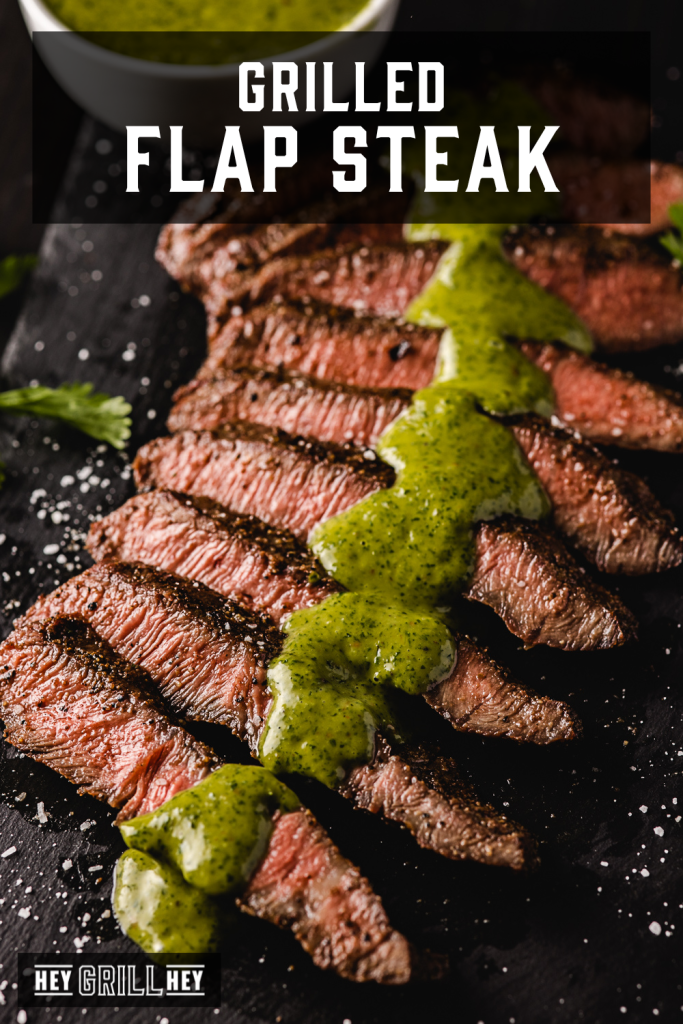 Sliced flap steak drizzled with cilantro chimichurri on a serving dish with text overlay - Grilled Flap Steak.