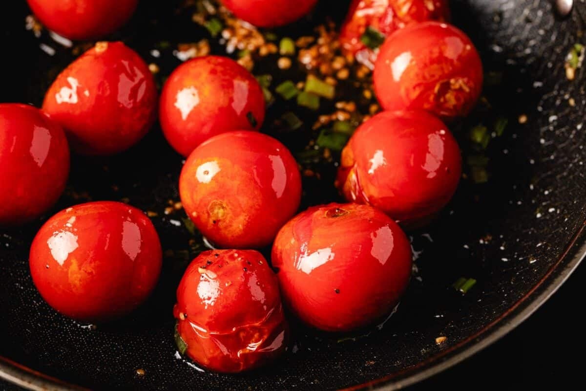 Tomatoes cooking in a cast iron skillet.