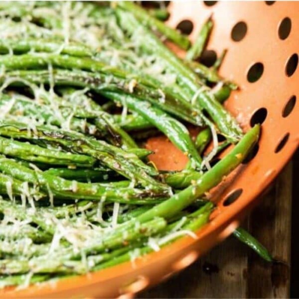 Parmesan covered grilled green beans in a copper vegetable grilling wok.