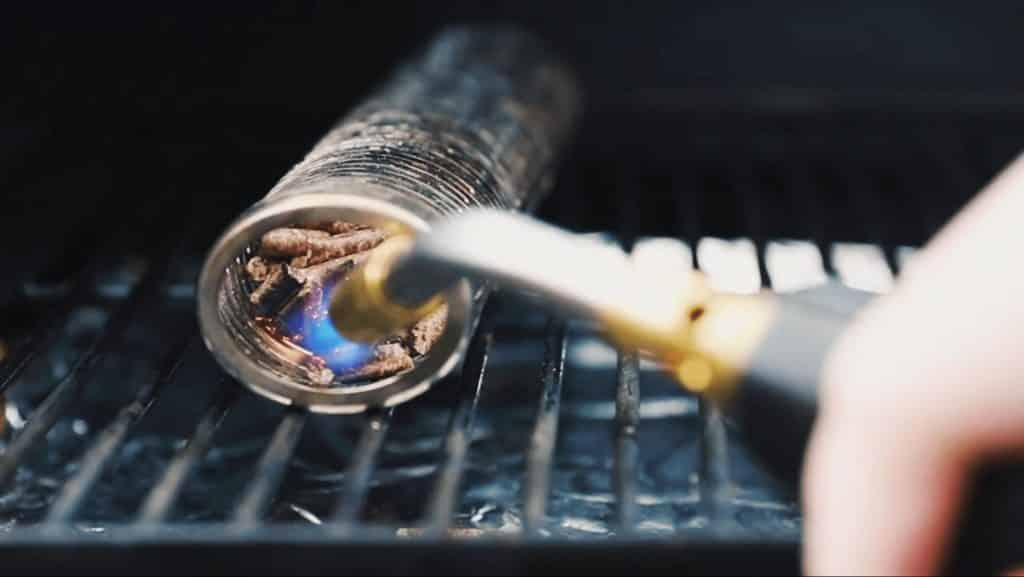 lighting a pellet smoke tube in a grill.