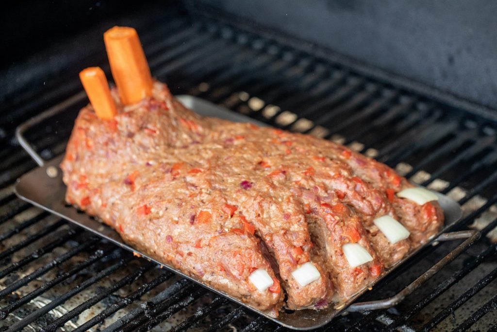 Ground beef shaped like a foot, on a metal tray inside the grill.