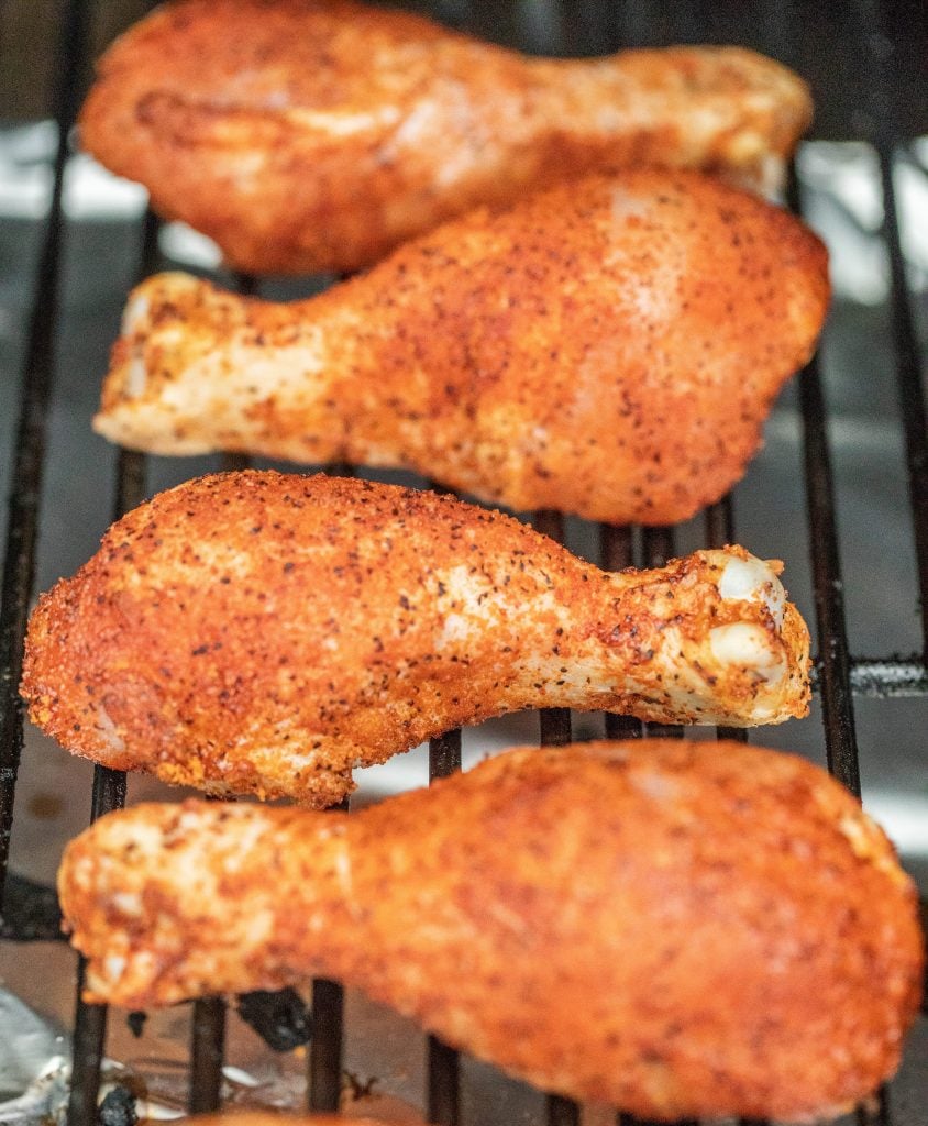 seasoned chicken legs on grill grates.